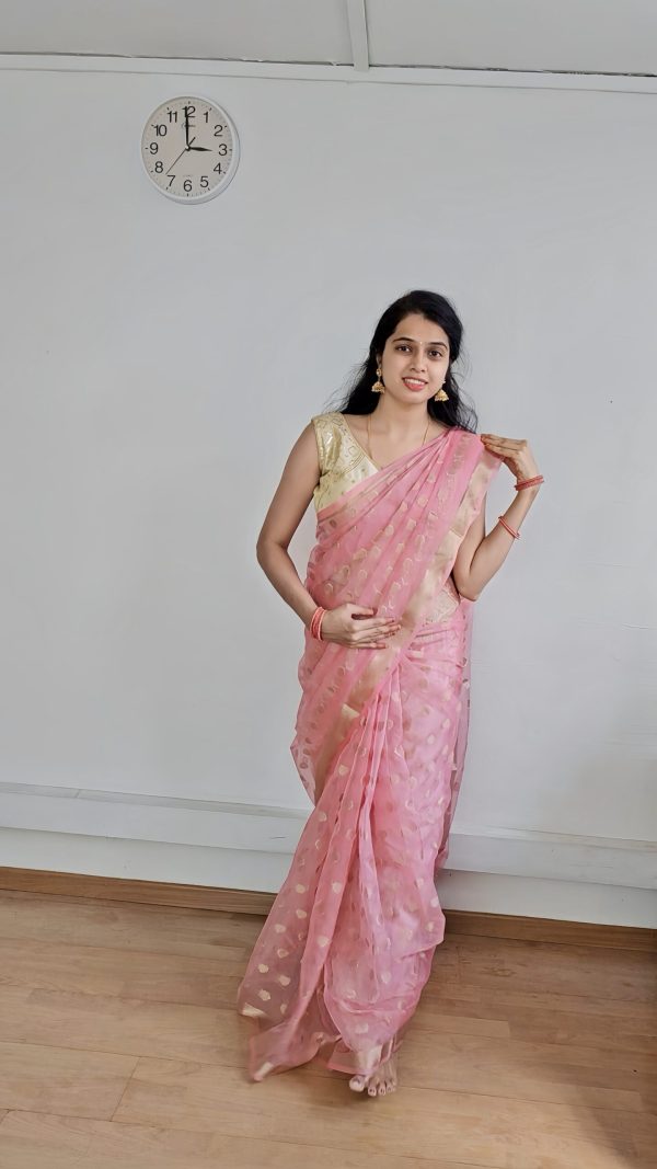 Woman wearing peach organza saree with golden butta – festive traditional wear