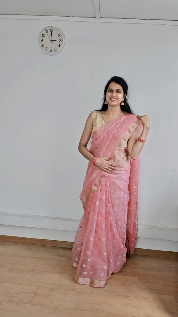 Woman wearing peach organza saree with golden butta – festive traditional wear